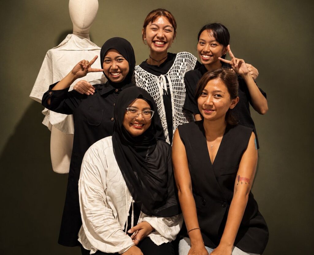 The friendly female design and management team of MARI Stitch clothing manufacturer in Bali, standing together in a studio.