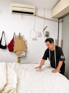 Professional tailor measuring and cutting fabric for bulk clothing production at MARI Garment manufacturer in Bali.