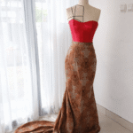 Stunning evening gown featuring a red sweetheart bodice and a patterned trailing skirt, showcasing premium dress manufacturing in Bali.