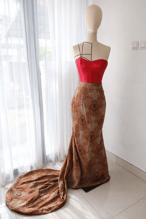 Stunning evening gown featuring a red sweetheart bodice and a patterned trailing skirt, showcasing premium dress manufacturing in Bali.